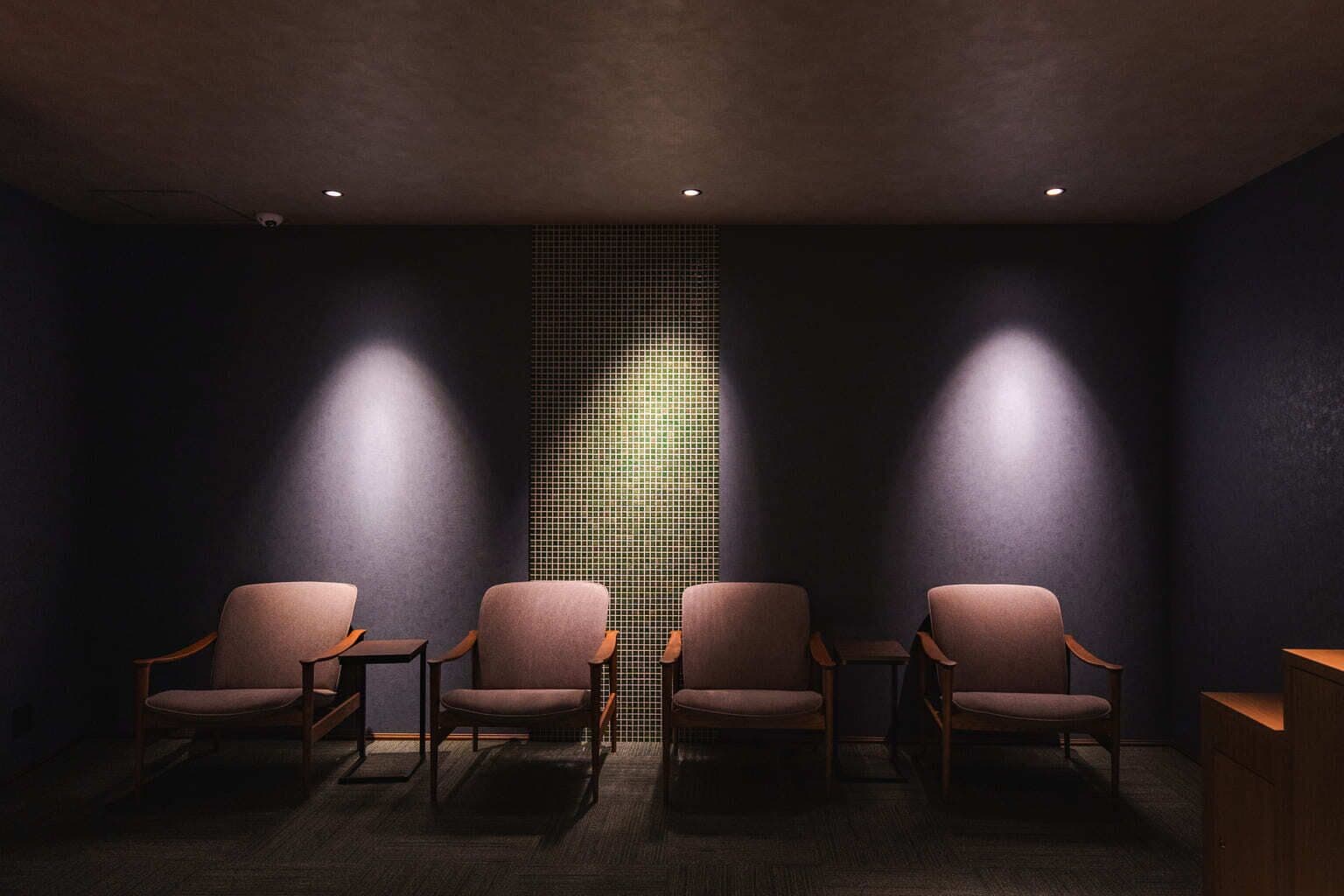 Quarto com quatro cadeiras e uma parede com padrão quadriculado.