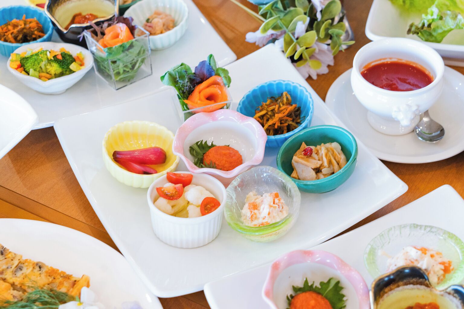 A variety of food items arranged on a table, including bowls of salad, vegetables, and other dishes.