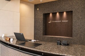 A reception desk with a laptop, a tablet, and a sign indicating the front desk area. - Rembrandt Resort Shiretoko (Shari)