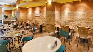 Un restaurant avec des tables et des chaises rondes, des murs en pierre et une décoration aux couleurs chaudes.