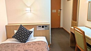Une chambre d’hôtel équipée d’un lit, d’un bureau, d’une chaise, d’un panneau de commande fixé au mur et d’une porte.