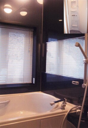 A bathroom with a bathtub, a shower, and a window with blinds. - Ryokan Yamaichi (Wakkanai)