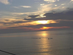 A sunset over a calm sea with two boats in the distance. - Ryokan Yamaichi (Wakkanai)