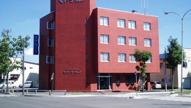A red building with multiple windows and a sign that reads "ビジネスホテル モトナカン". - Business Hotel Motonakano (Tomakomai)