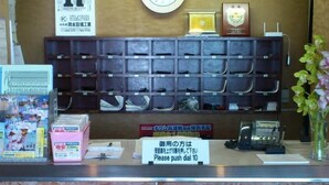 A reception desk with a clock, a sign indicating the room number 17, and a push-dial phone. - Business Hotel Motonakano (Tomakomai)