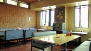 A restaurant with booths and tables, wooden walls, and large windows. - Business Hotel Motonakano (Tomakomai)