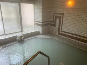 A hot spring area with a tiled wall, a window, and a metal railing.