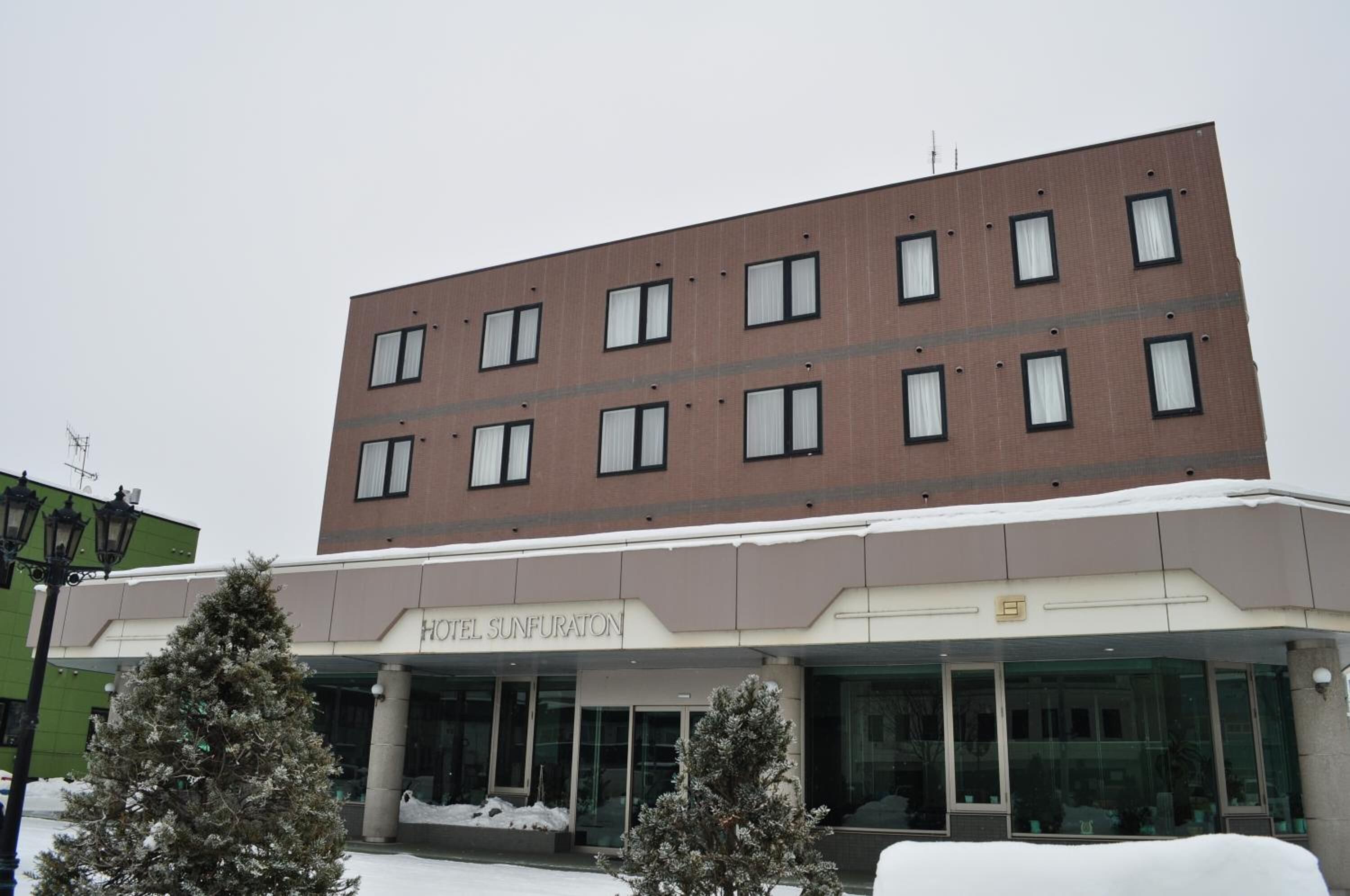 A modern hotel building with a flat roof and multiple windows.