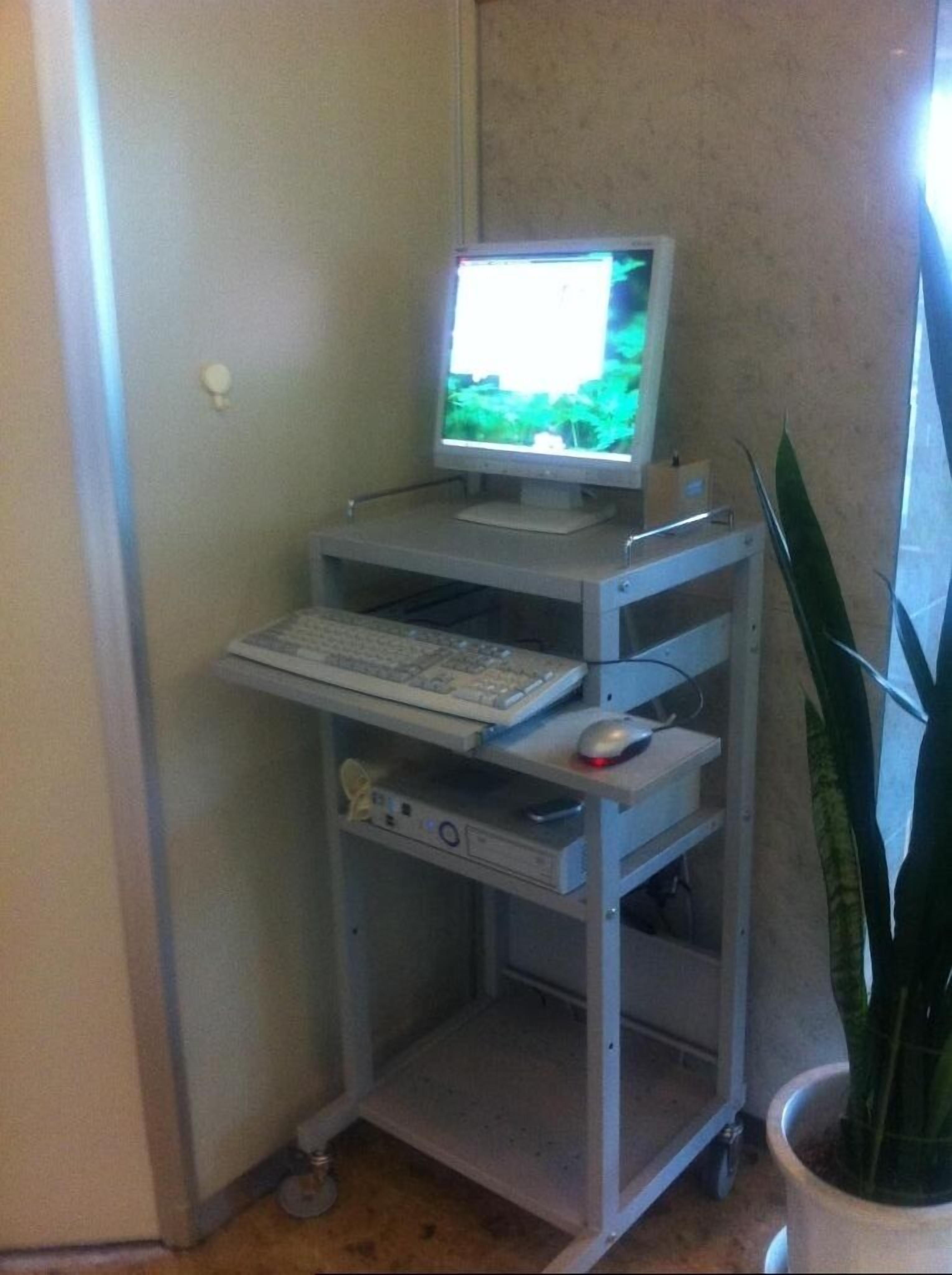 Ett rum med ett skrivbord, en dator och ett litet fönster.