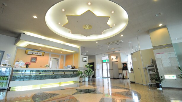A hotel reception area with a modern design, including a star-shaped ceiling light, a reception desk, and a glass display case. - Hotel Sunfuraton (Furano)