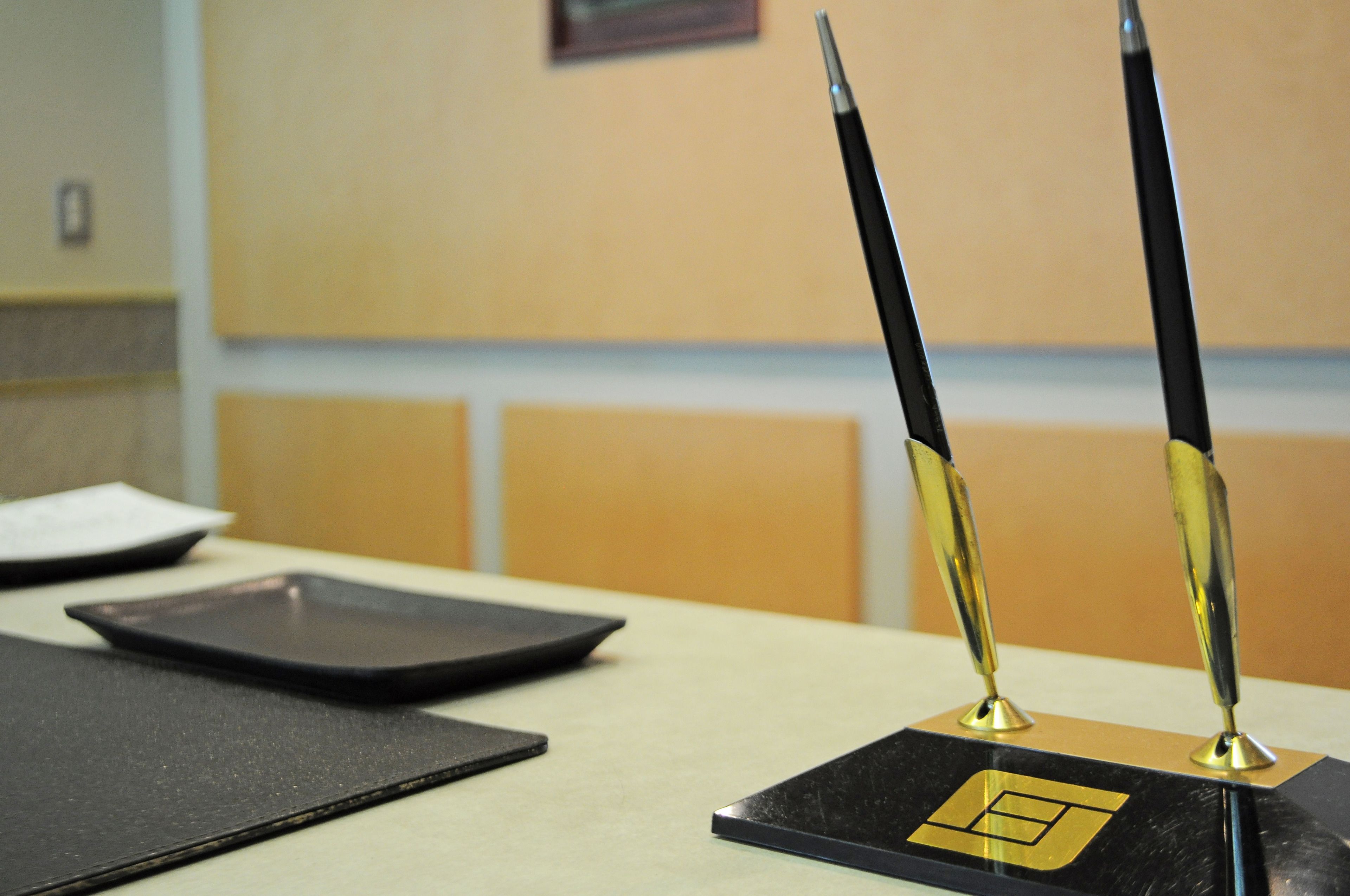 A black and gold desk with two black pens standing upright.