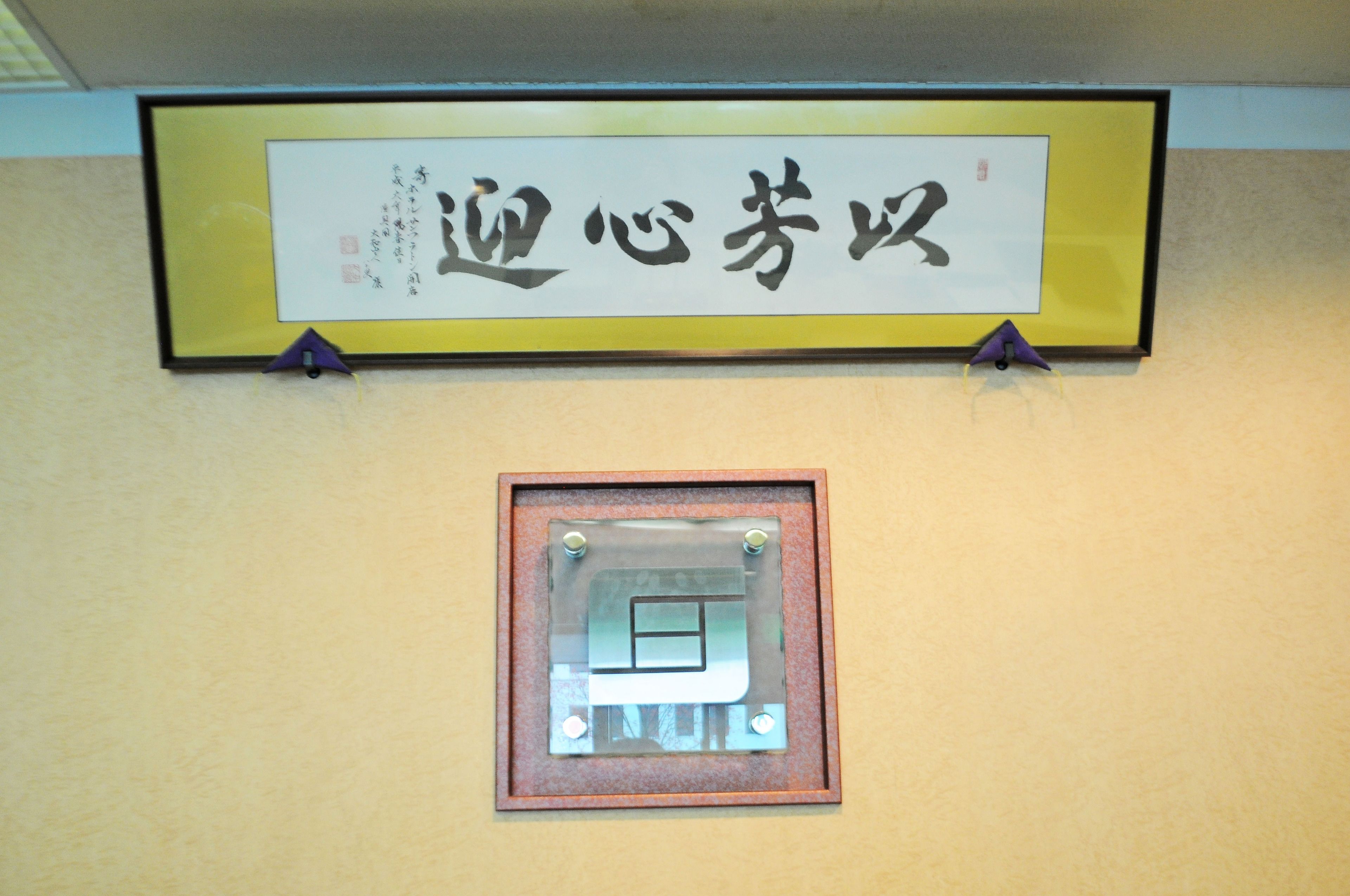 Une plaque encadrée avec des caractères chinois, et un objet plus petit, également encadré, placé en dessous.