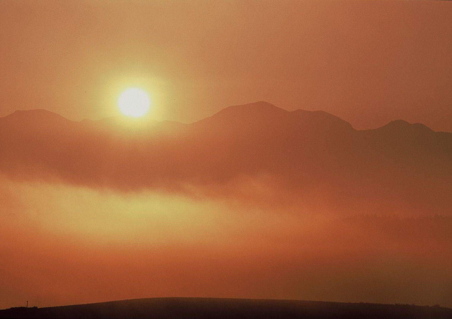 Un atardecer sobre una cadena montañosa bajo un cielo despejado.