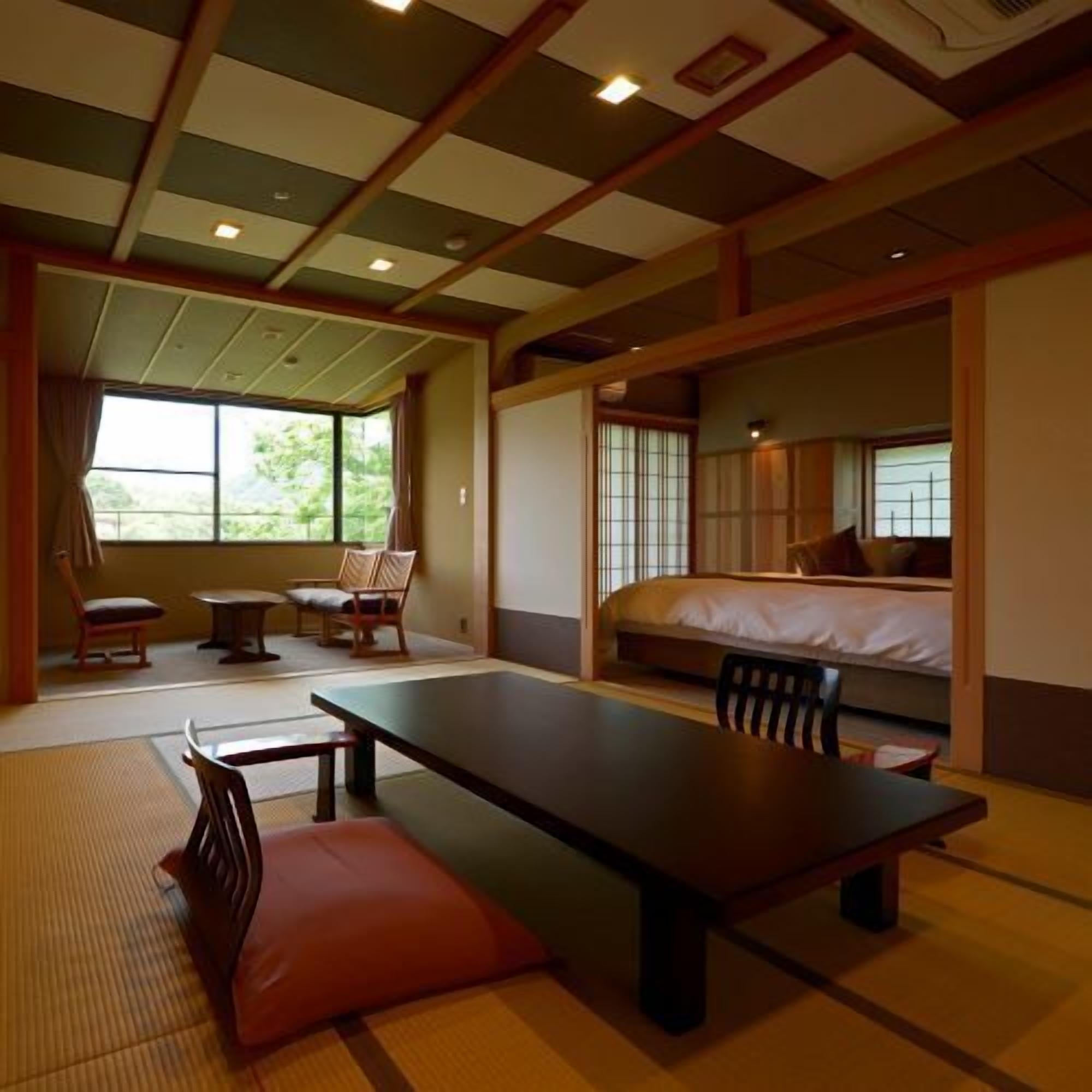A traditional Japanese-style room with tatami flooring, a low table, chairs, and a bed with a futon.