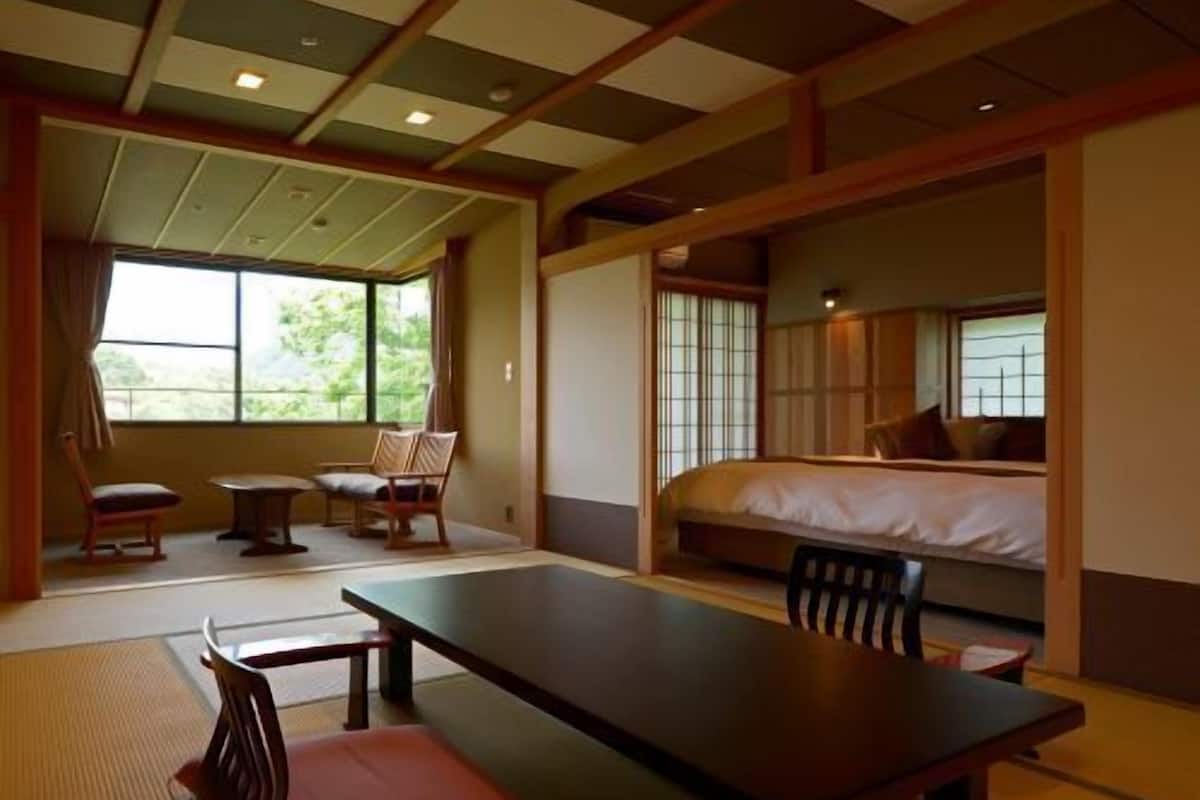 Une pièce de style japonais traditionnel, avec un sol recouvert de tatamis, une table basse, des chaises et un lit équipé d’un futon.