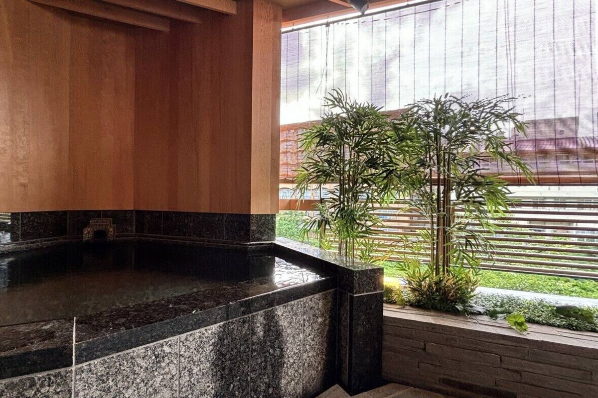 A spa area with a hot tub, wooden paneling, and a view of a building through a window.