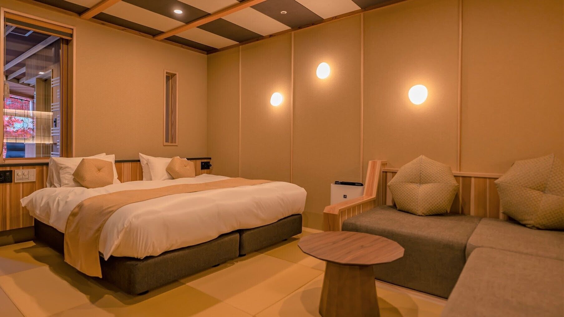 Una habitación de hotel con cama, sofá, una mesita y ventana con persianas.