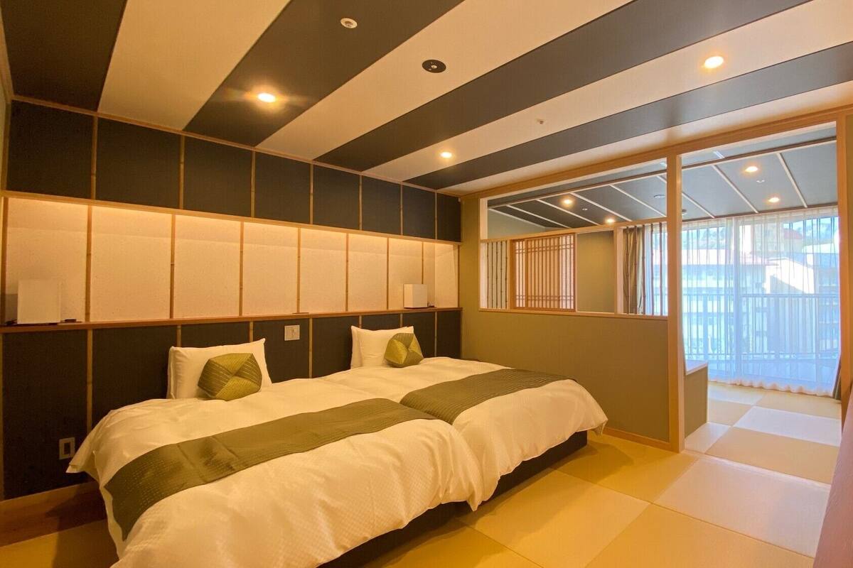 A hotel room with a bed, a desk, and a view of the outside.