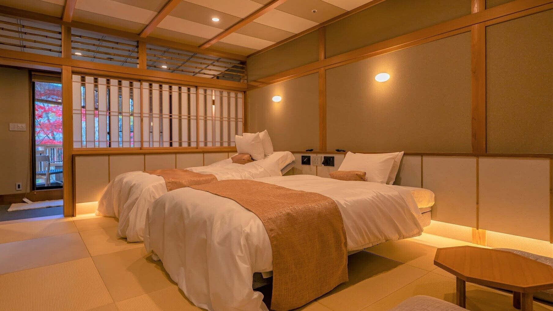Una habitación tradicional japonesa con suelo de tatami, una cama baja de madera con ropa de cama blanca y una puerta corredera de shoji.