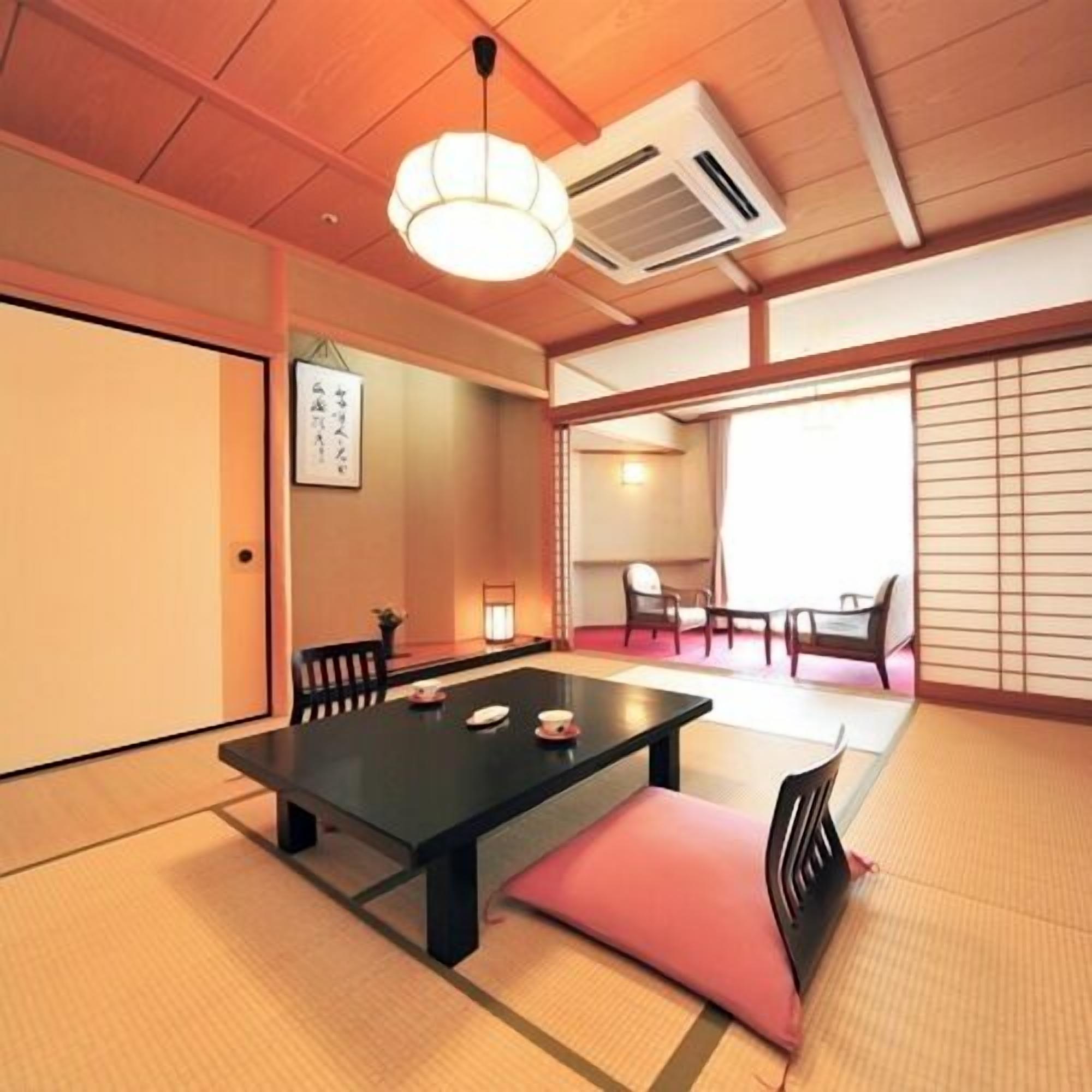 Una habitación japonesa tradicional con suelo de tatami, una mesa baja y puertas correderas.