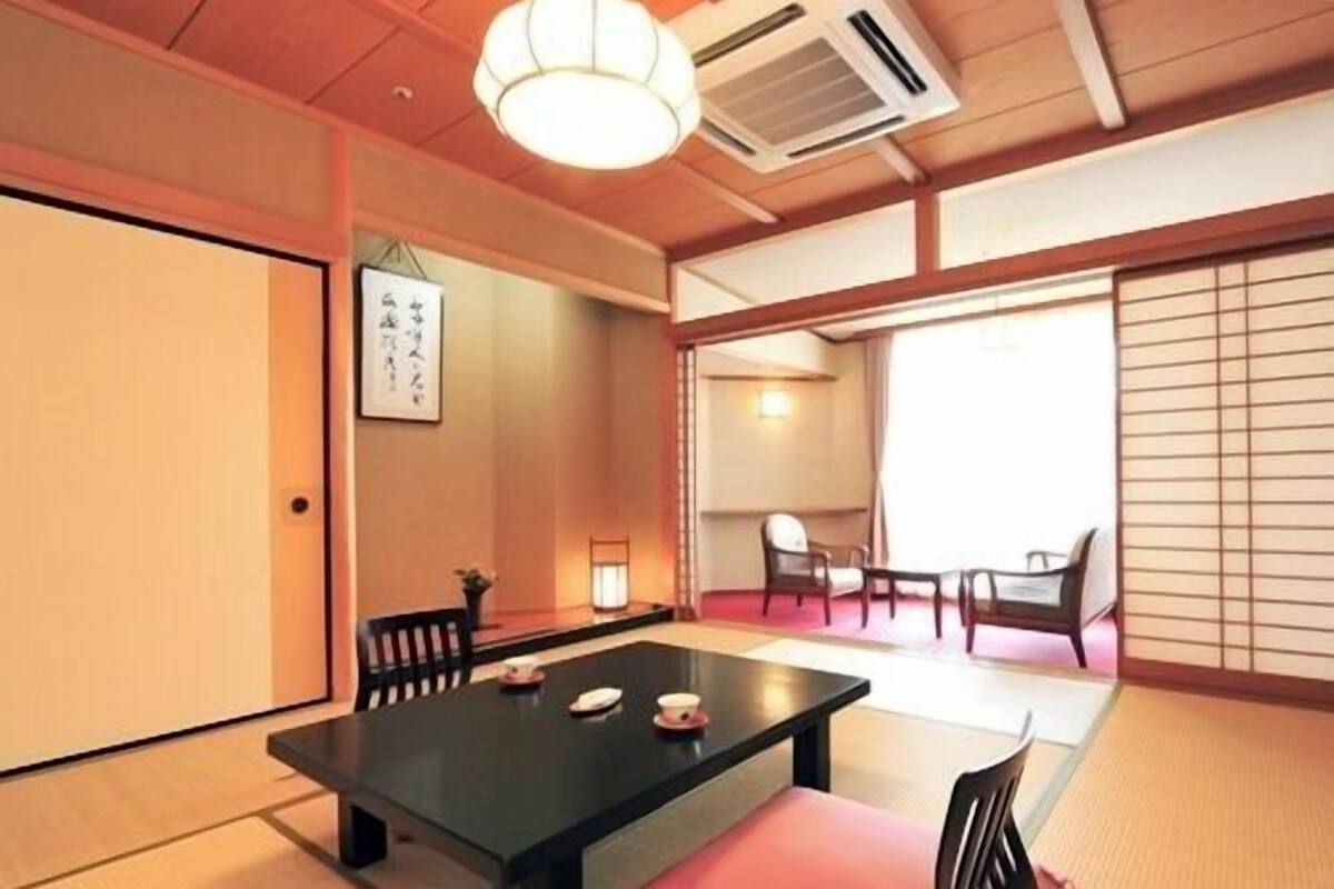 A traditional Japanese room with tatami flooring, a low table, and sliding doors.