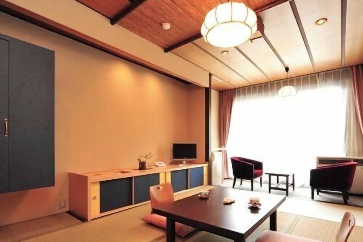 A traditional Japanese room with tatami flooring, a low table, and a sofa.