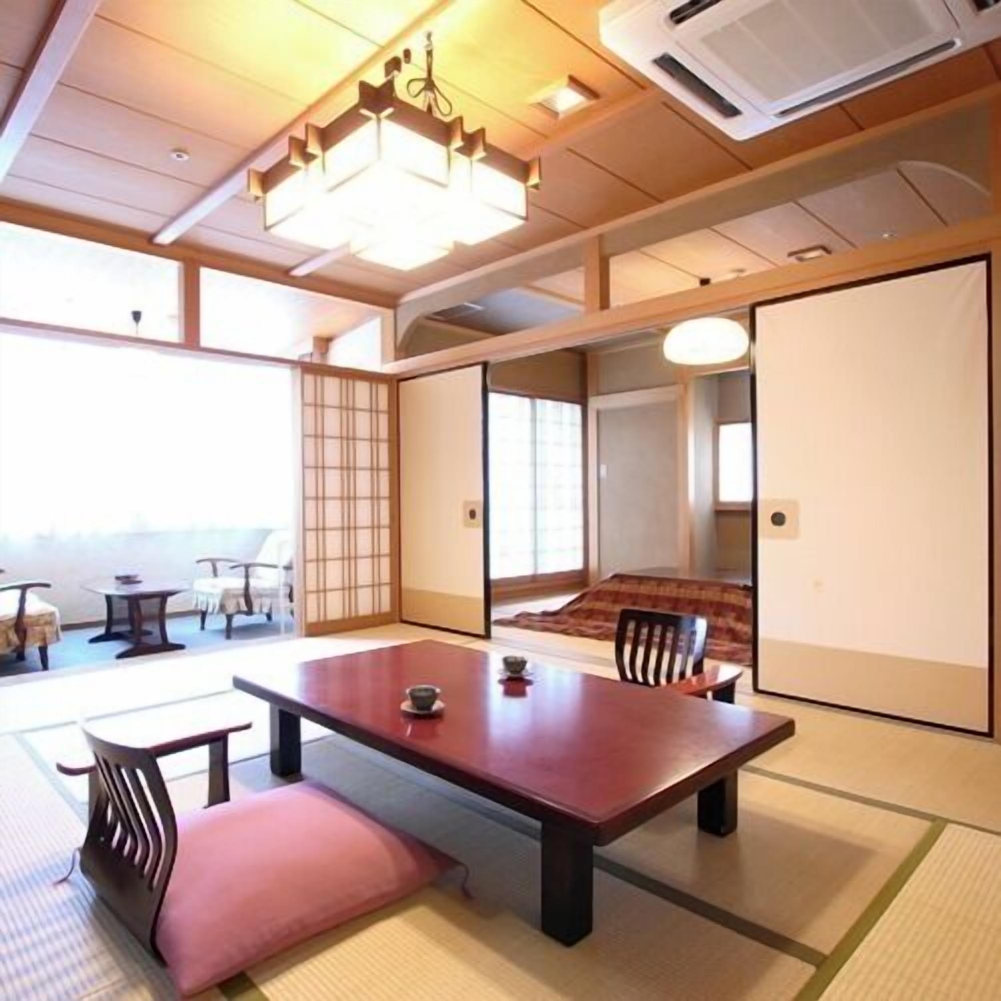 Una habitación japonesa tradicional con suelo de tatami, una mesa baja con cojines y puertas correderas.