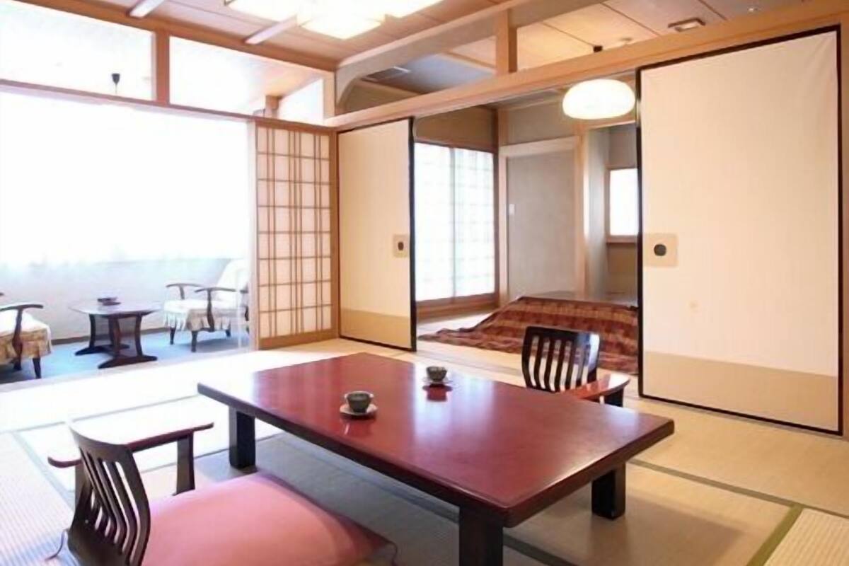 A traditional Japanese room with tatami flooring, a low table with cushions, and sliding doors.