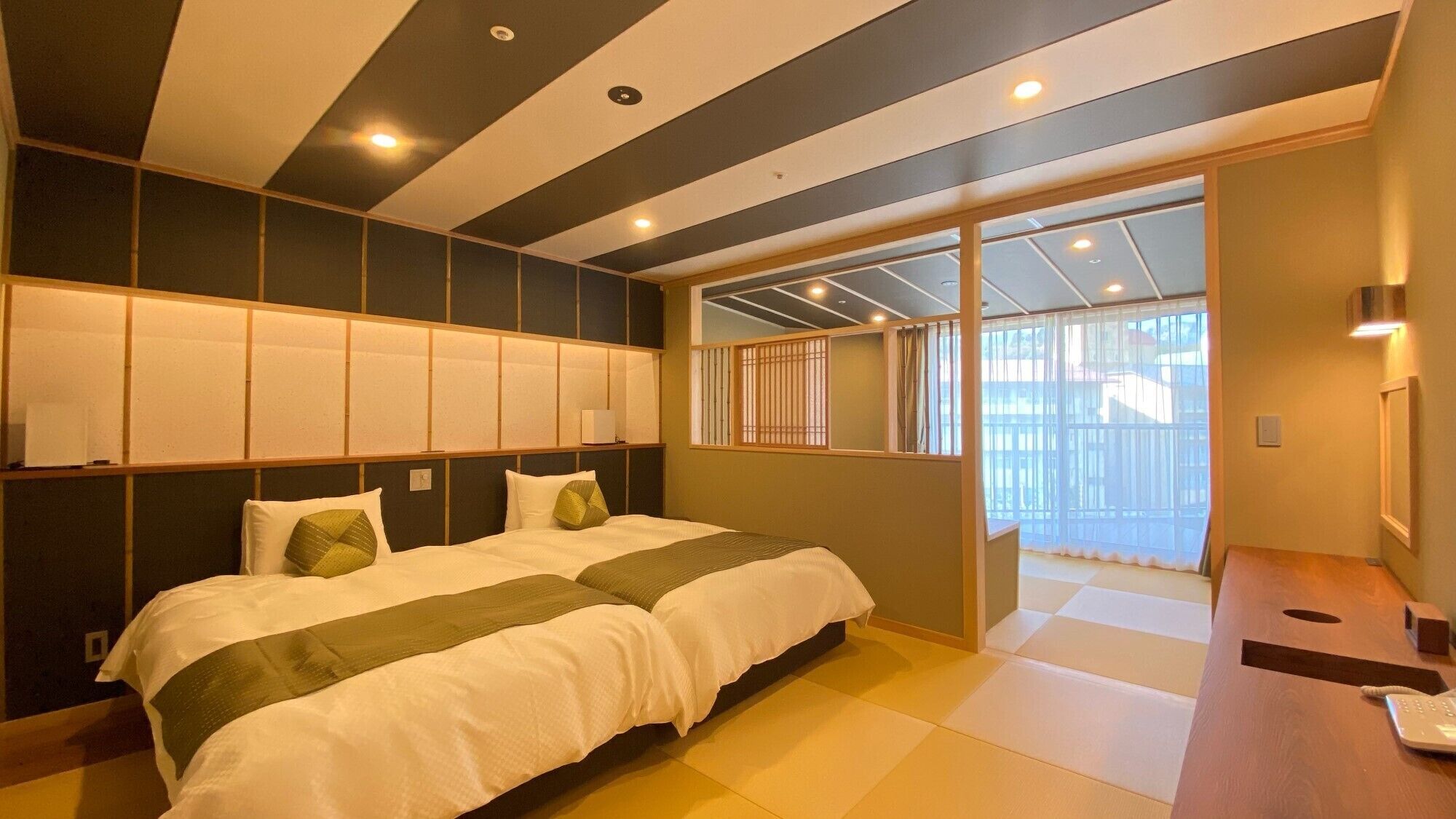 Una habitación de hotel con cama, escritorio con teléfono y vista por la ventana.