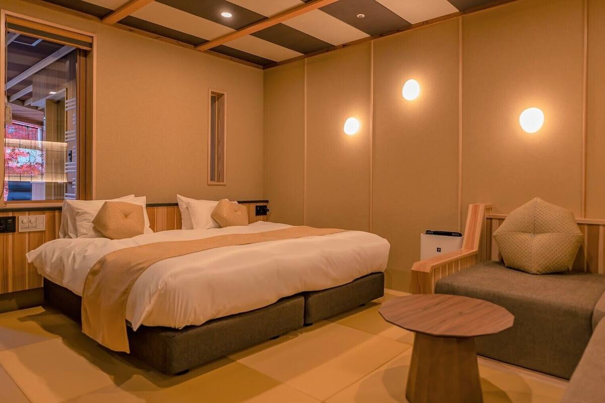 A hotel room with a bed, a sofa, a small table, and a window with a view.