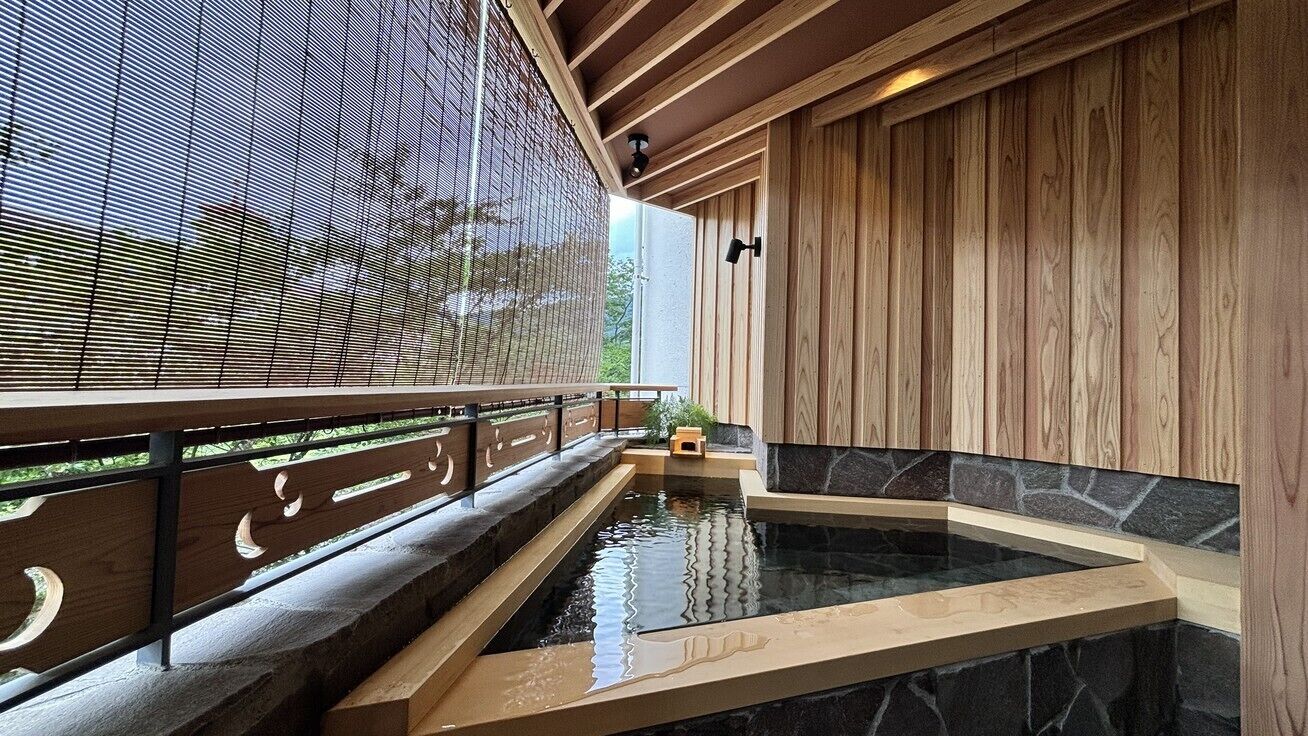 A spa area with a hot tub, wooden paneling, and a view through a mesh screen.