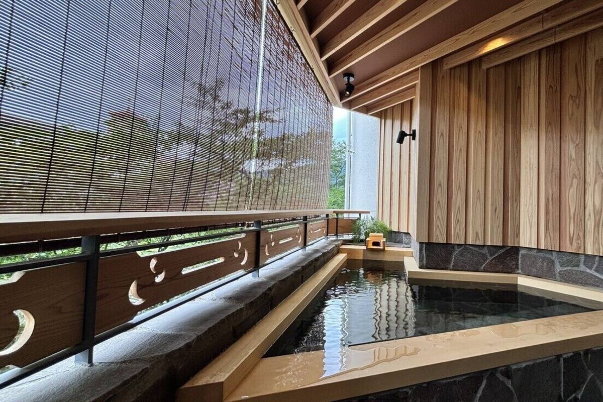 A spa area with a hot tub, wooden paneling, and a view through a mesh screen.