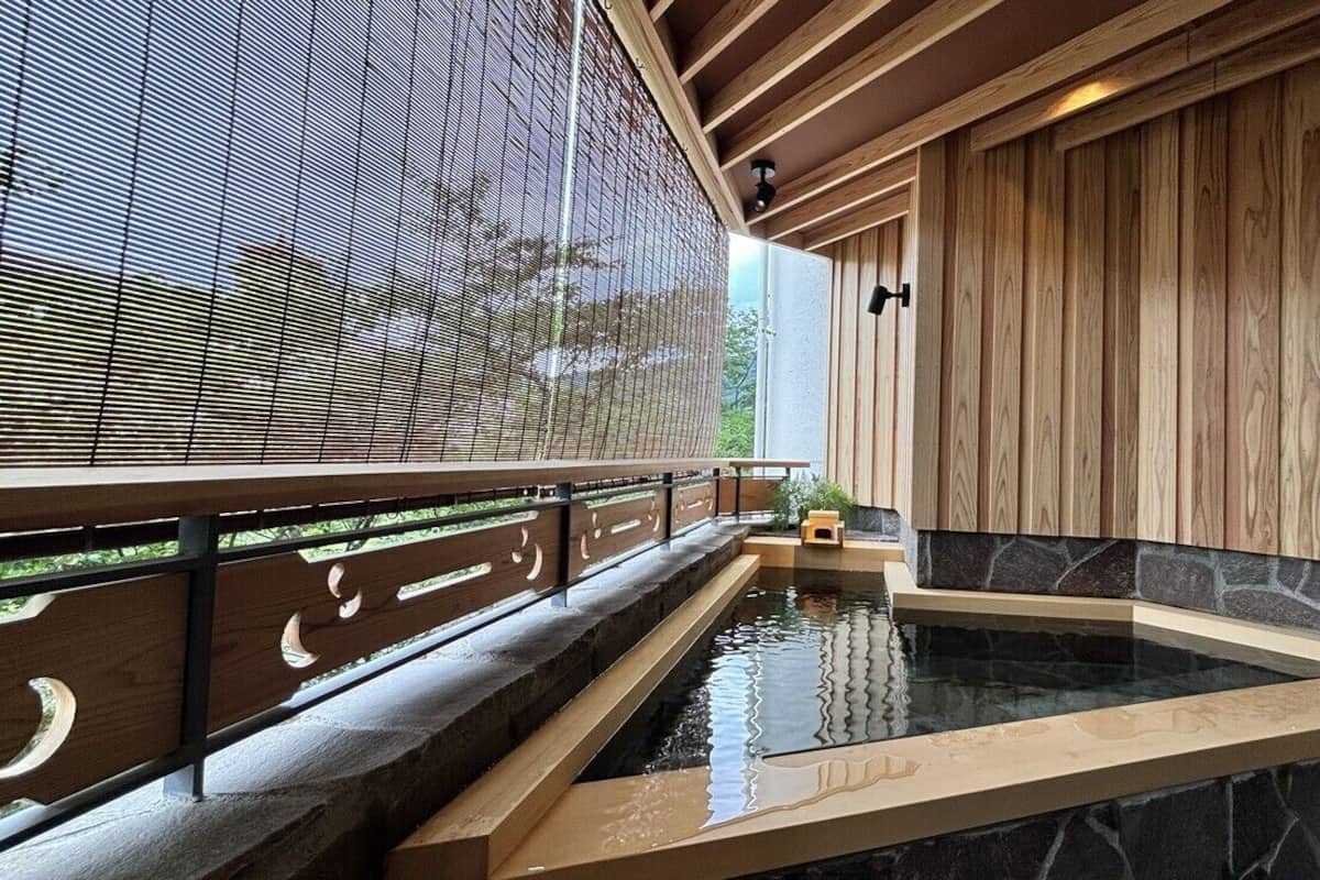 Un espace bien-être comprenant un jacuzzi, un revêtement mural en bois et une vue à travers un écran ajouré.