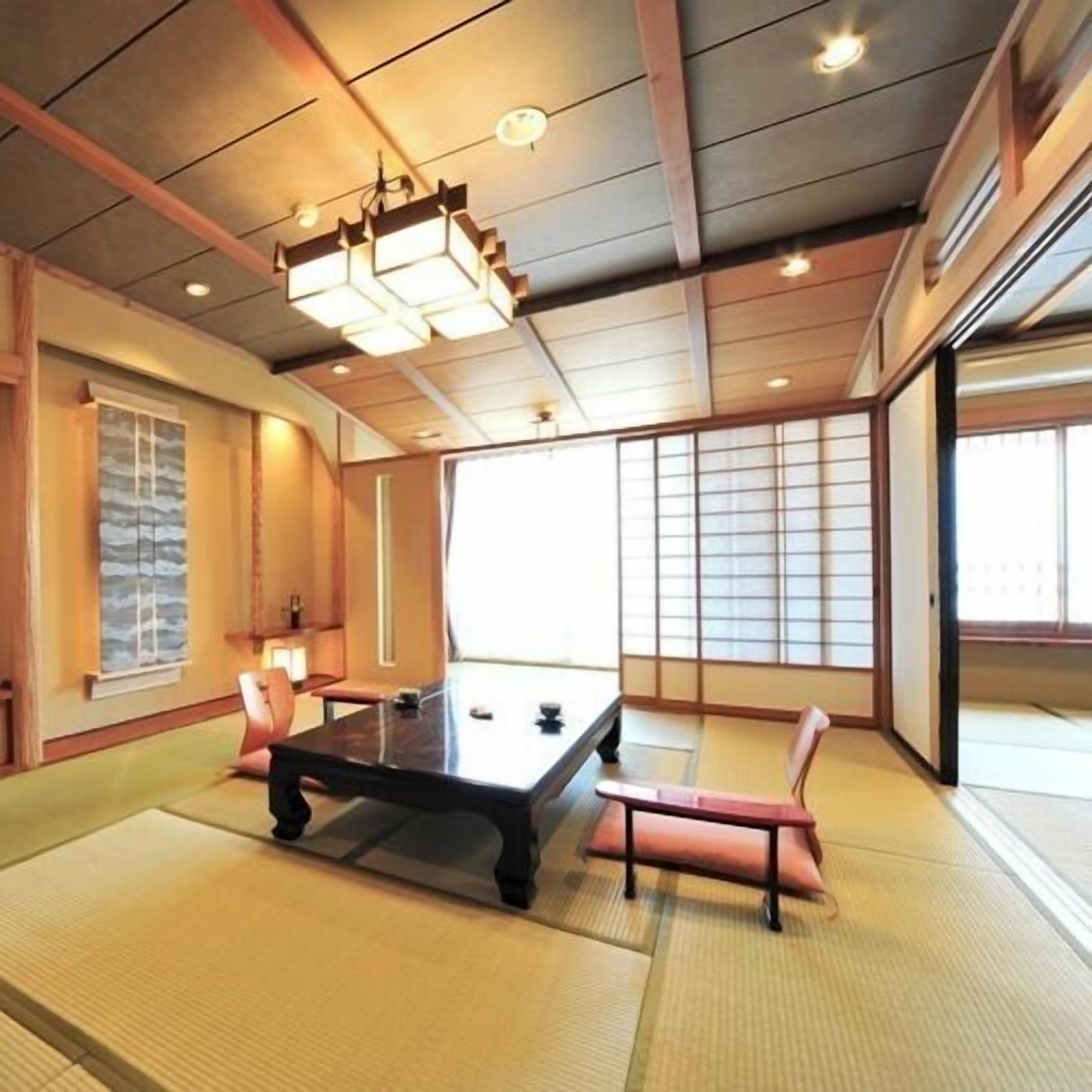 Una habitación con suelo de tatami, una mesa baja, cojines, puertas correderas y una lámpara en el techo.