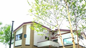 A multi-story building with a flat roof and a balcony. - Pension ASHITAYA (Furano)