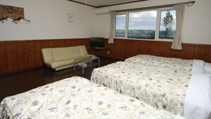 A room with two beds, a sofa, a television, and a window with a view. - Pension ASHITAYA (Furano)