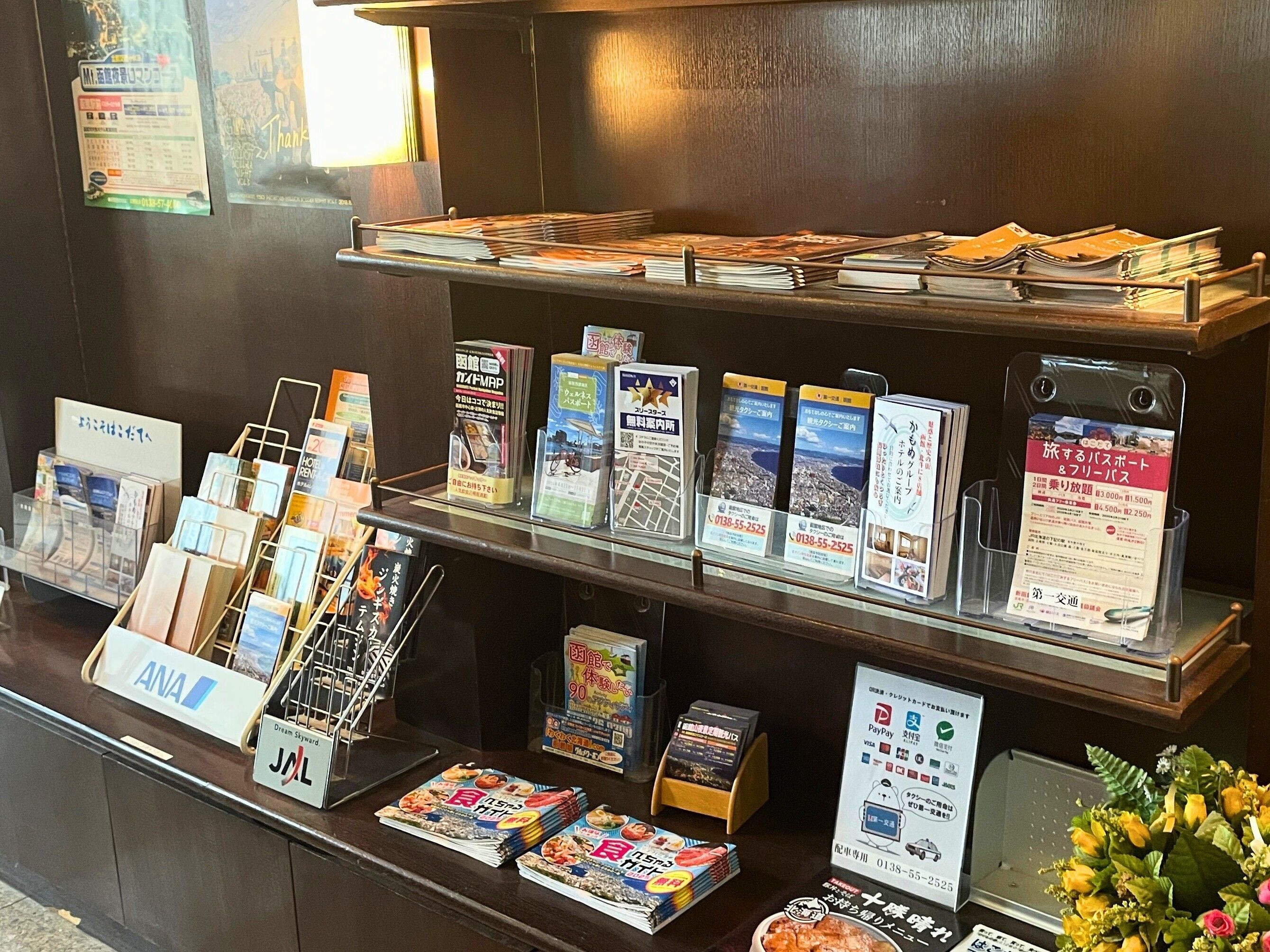 Un comptoir d’accueil avec divers dépliants d’information, une plaque nominative et un menu.