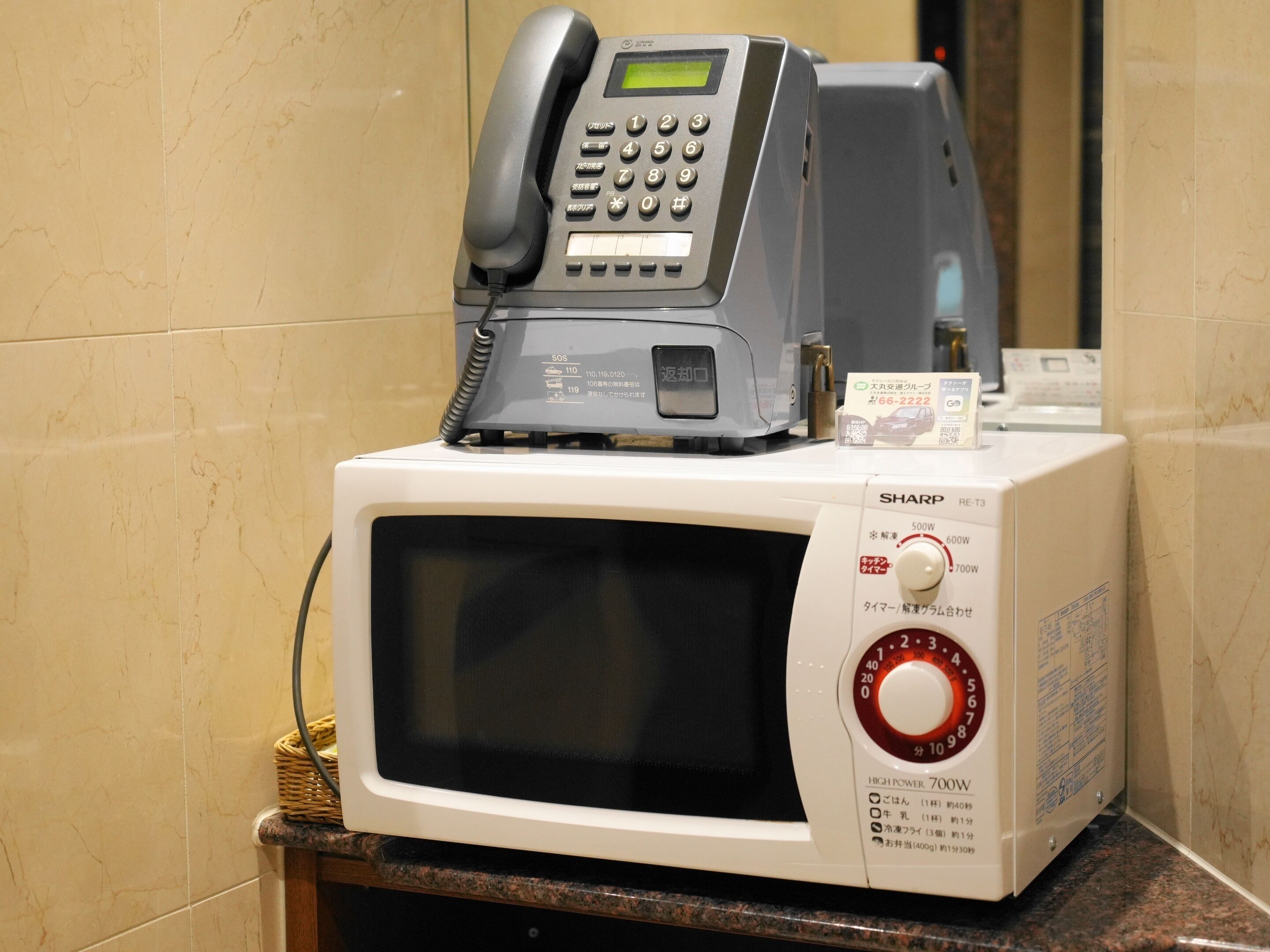 A microwave oven with a telephone on top.