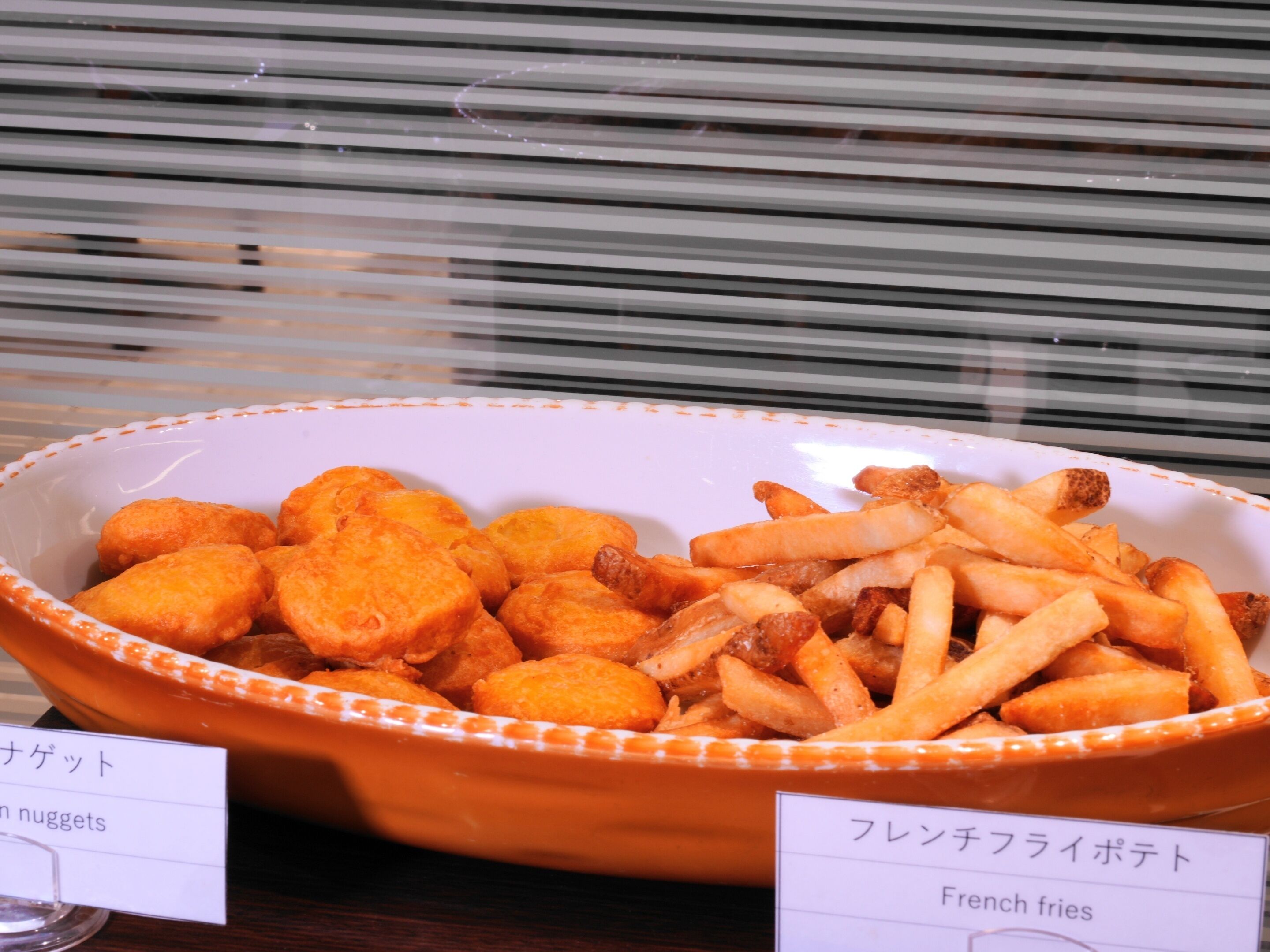 Un bol contenant des aliments, avec des étiquettes indiquant « nuggets » et « frites ».