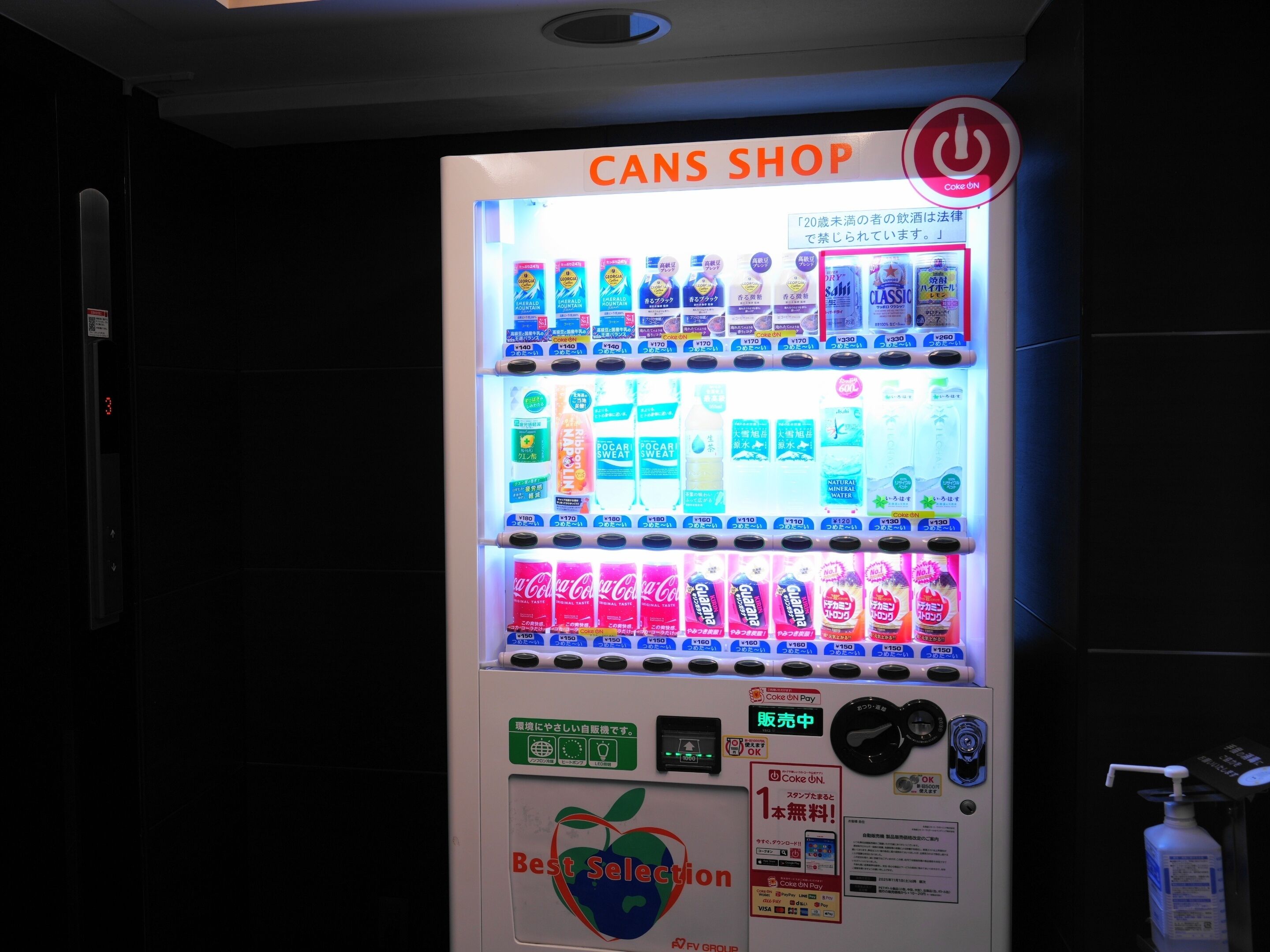 Un distributeur automatique portant l’inscription « BOISSONS » et proposant différents types de boissons et différentes méthodes de paiement.