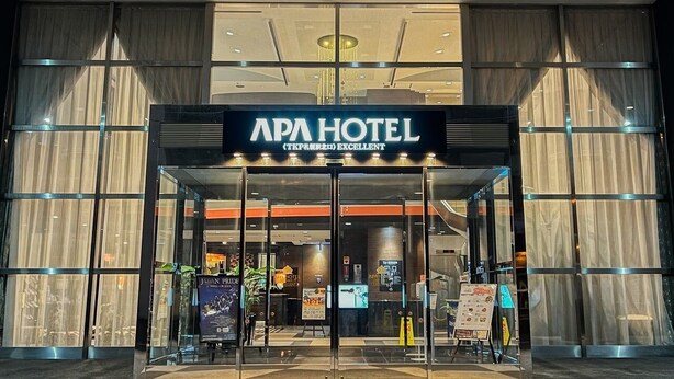 Entrada do APA HOTEL com design moderno, grandes portas de vidro e uma placa indicando ser um estabelecimento 5 estrelas.
