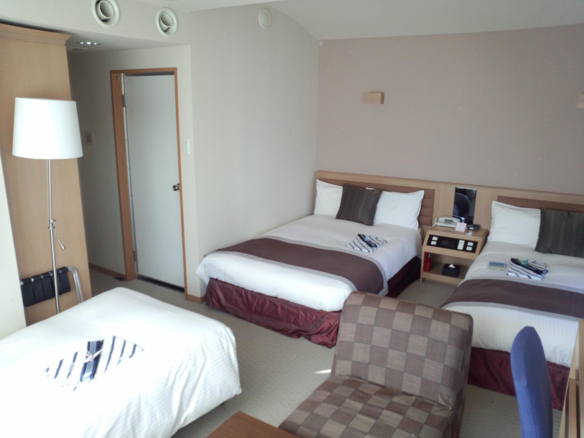 Una habitación de hotel con dos camas, un escritorio, una silla y una lámpara.