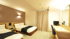 Quarto de hotel com duas camas, uma escrivaninha com computador, telefone e espelho.