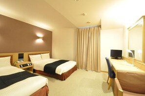Quarto de hotel com duas camas, uma escrivaninha com computador, telefone e espelho.