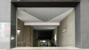 Entrada de estacionamento com placa indicando 'PARKING IN'.