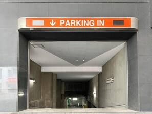 Entrada de estacionamento com placa indicando 'PARKING IN'.