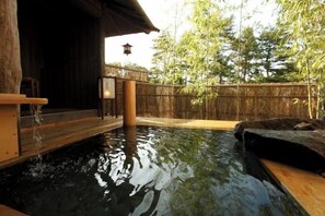 A hot spring area with a wooden deck, a stone platform, and a bamboo fence. - Konoha (Kusatsu)