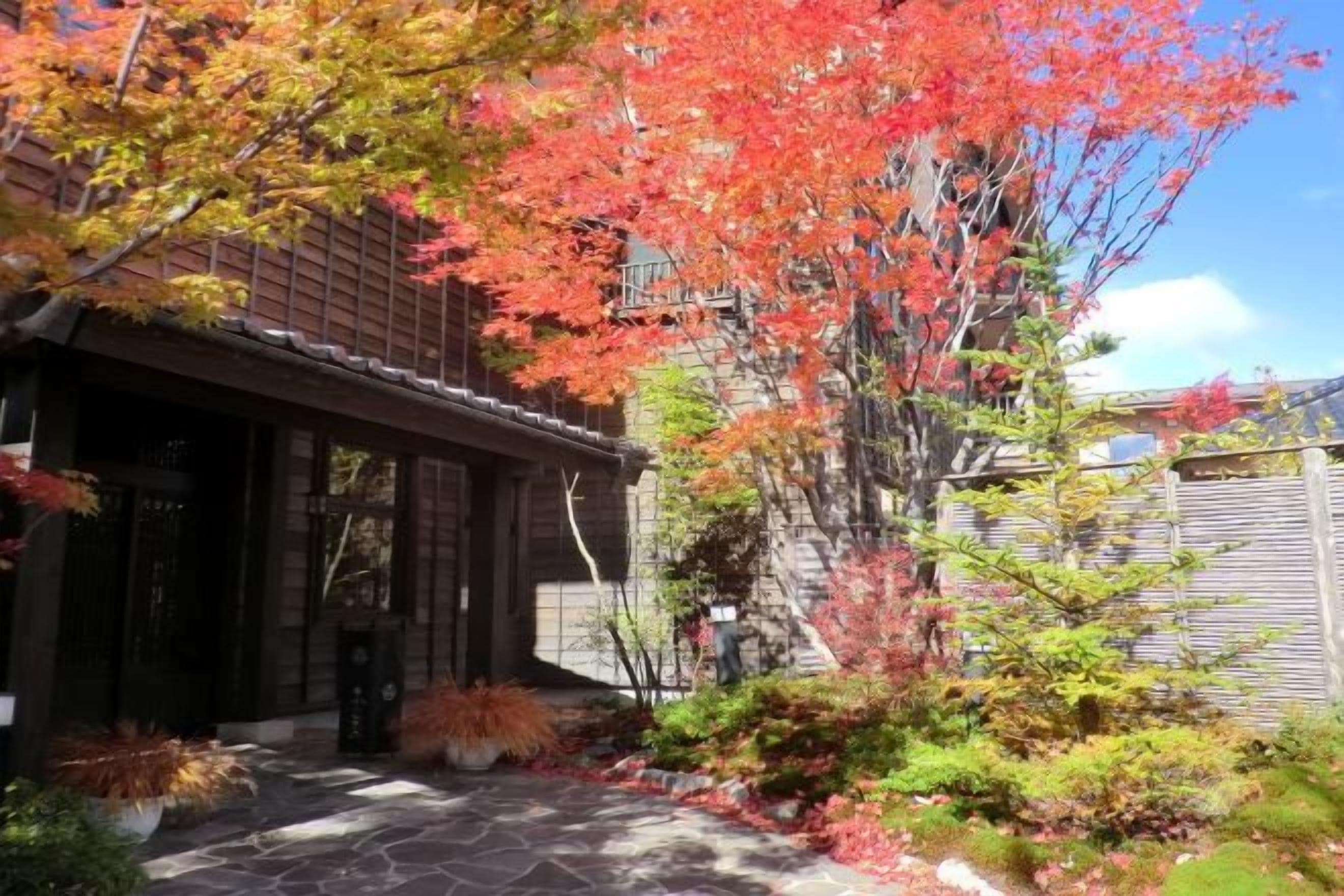 A traditional building with a stone pathway leading to the entrance, surrounded by autumn foliage.