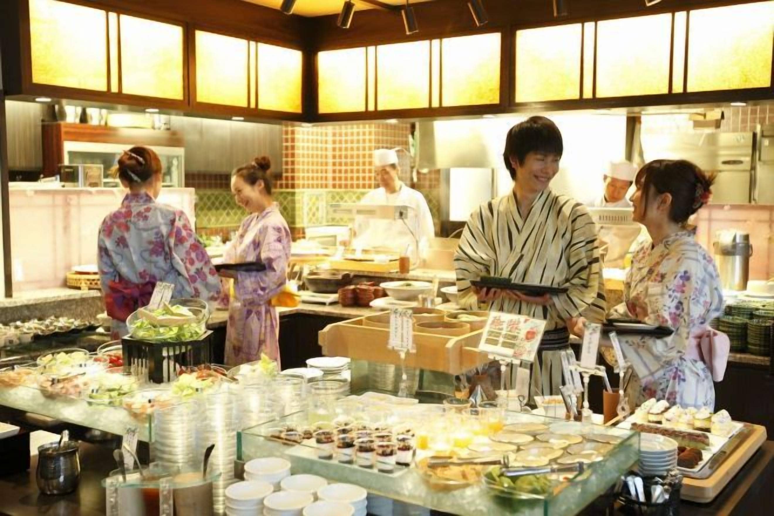 A buffet setup with various food items and a group of people in traditional attire.