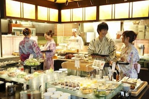 A buffet setup with various food items and a group of people in traditional attire.